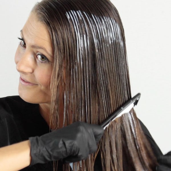 woman with brown hair applying hair toner