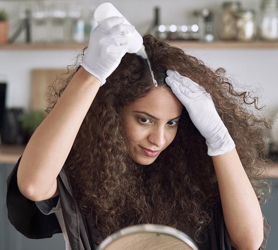 Woman with curly hair applying hair color to roots